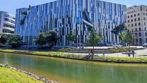 A modern building with a unique facade, surrounded by a landscaped area with a water feature. - Candlewood Suites Dusseldorf Airport by IHG (Düsseldorf)