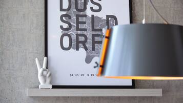 A framed map with text and coordinates on a wall, a small white sculpture, and a modern lamp.