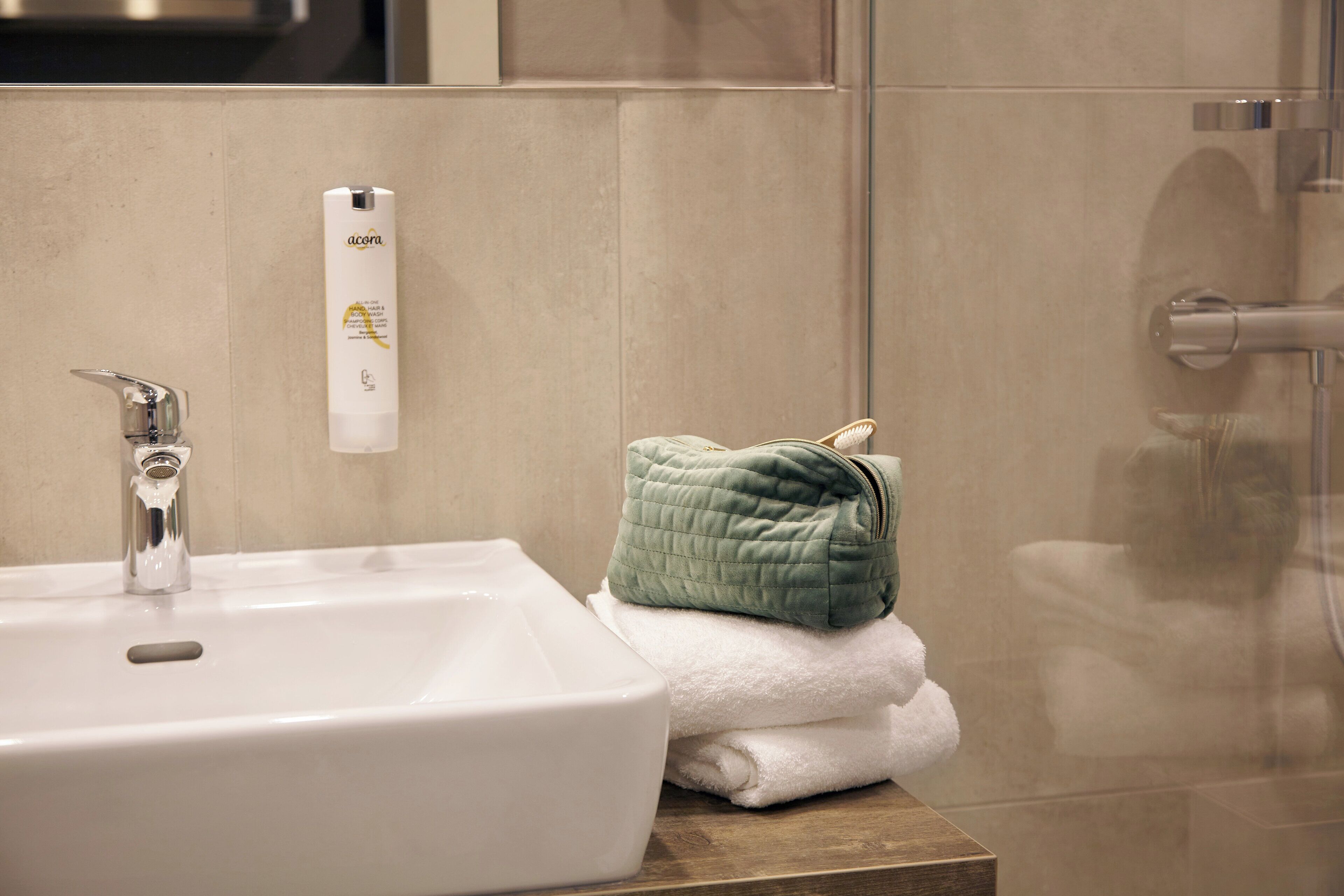 A bathroom with a white sink, a green towel, and a white bottle of lotion on the counter.
