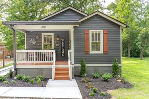 A two-story house with a front porch, a mailbox, and a welcome sign.