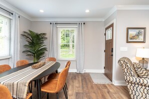 Un comedor con una mesa, sillas, una planta y una puerta que da a otra habitación.