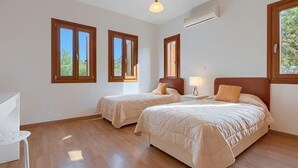 Une chambre avec deux lits, un plancher en bois et de grandes fenêtres.