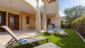 Une villa moderne dotée d’un patio couvert, d’un espace salon extérieur et d’une pelouse bien entretenue.