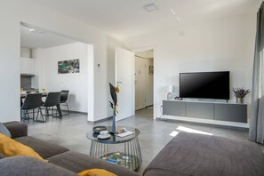 A modern living room with a flat-screen TV, a dining area with chairs, and a sofa. - Villa Dora - Apartment 3 "Grey" with balcony (Pula)