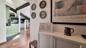A modern kitchen with a microwave, a sink, and a dining area with a table and chairs. There is a framed artwork on the wall and a cabinet with a pitcher on top. - Italianway Easy - Fauch 9 (Milan)