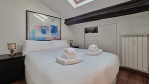 A hotel room with a large bed, a painting on the wall, a nightstand, a dresser, and a radiator. - Italianway Easy - Fauch 9 (Milan)