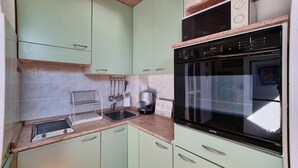 A kitchen with light green cabinets, a stainless steel sink, a coffee maker, and a black oven. - Italianway Easy - Fauch 9 (Milan)