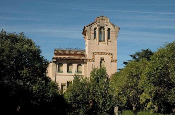 A historic building with a prominent tower, surrounded by lush greenery.