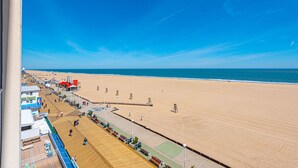 Una playa con un paseo marítimo de madera, sillas y sombrillas.