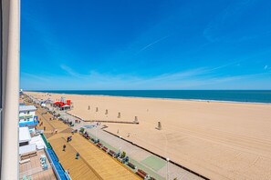 Una spiaggia con una passerella di legno, sedie a sdraio e ombrelloni.
