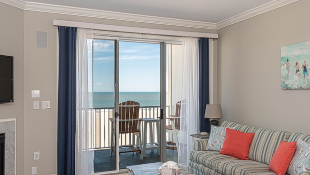 Una habitación con vista al océano, un sofá a rayas, una mesita y una silla junto a la ventana.