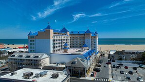 Un hotel grande con múltiples torres, un estacionamiento y una playa al fondo.