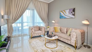 Una sala de estar moderna con un sofá color beige, una mesa redonda de centro y un ventanal con cortinas.