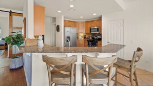 Una cocina con gabinetes de madera, encimera de granito y una isla central con taburetes de bar.