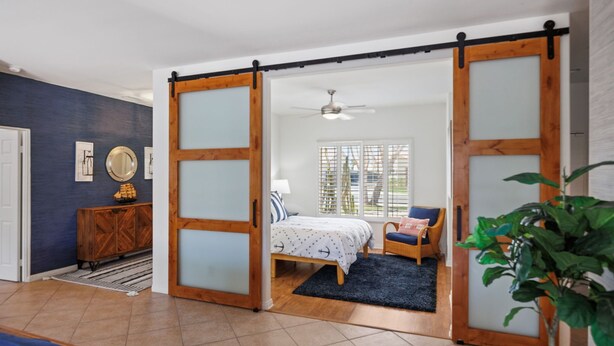 Una habitación con cama, una silla, un armario de madera y una puerta corredera.