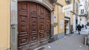 A large wooden door with a number '4' above it, a 'no parking' sign, and a building with a sign reading 'Gransicily'. - Central Pop House by Wonderful Italy (Torino)