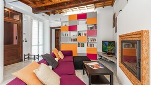 A living room with a wooden ceiling, a purple sofa, a bookshelf, and a television. - Central Pop House by Wonderful Italy (Torino)
