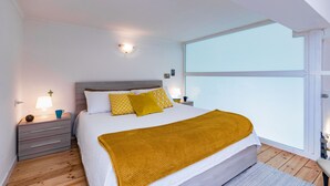 A bedroom with a large bed, a nightstand, a lamp, and a view of the sky through a large window. - That's a Mole by Wonderful Italy (Torino)