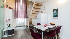 A compact kitchen with a dining area, wooden staircase, and a refrigerator. - That's a Mole by Wonderful Italy (Torino)