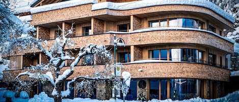 Un edificio de varios pisos con fachada curva, balcones de madera y alrededores nevados.