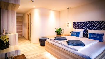Ein modernes Schlafzimmer mit einem großen Bett, einem kleinen Nachttisch, einer Topfpflanze und einer hängenden Deckenleuchte.