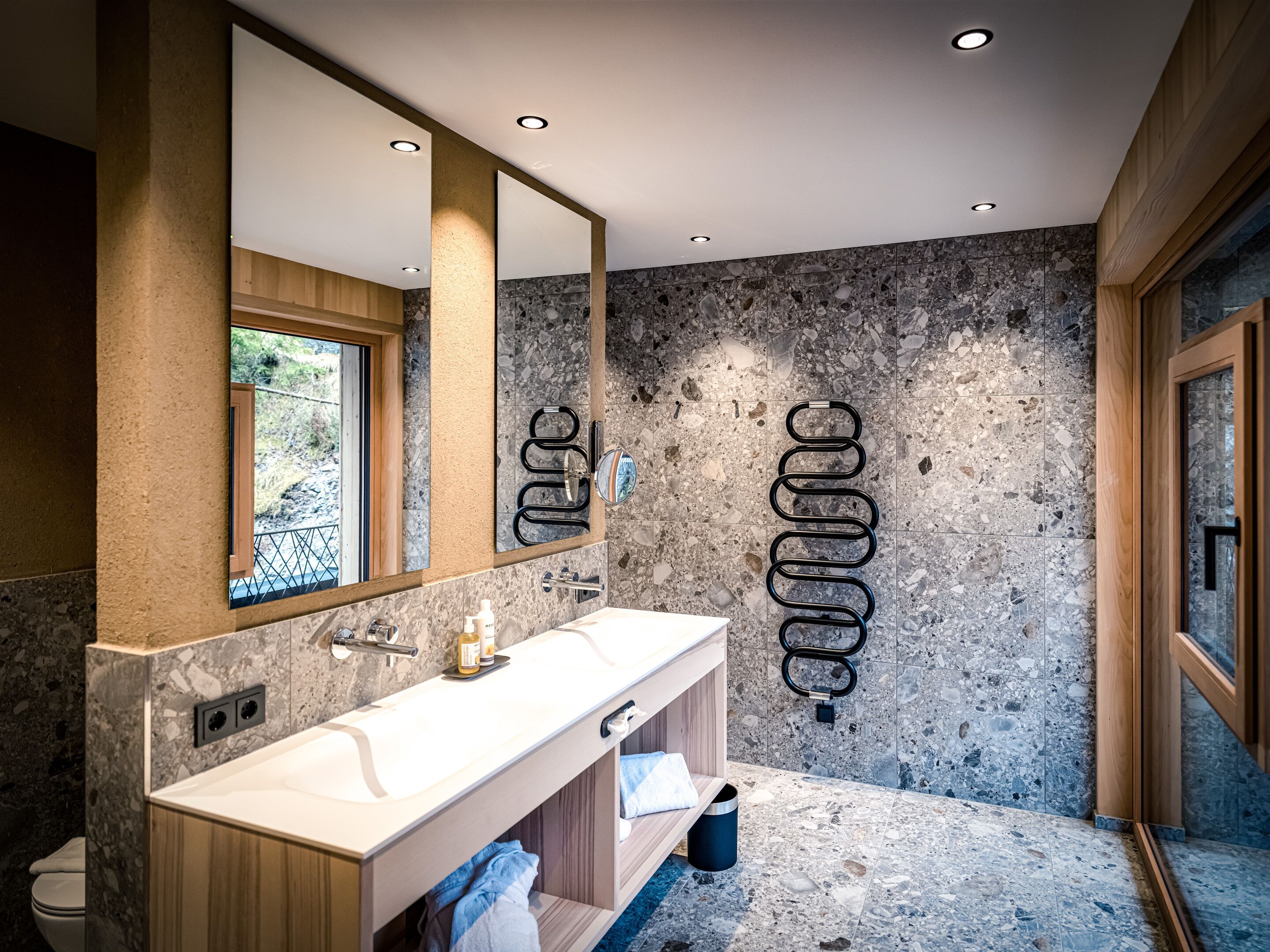 A modern bathroom with a large mirror, a white sink, and a marble backsplash.