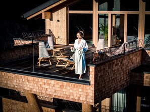 A wooden deck with lounge chairs and a person in a bathrobe. - HAUSEREI Design & Kräuterhotel - ADULTS ONLY (Steeg)