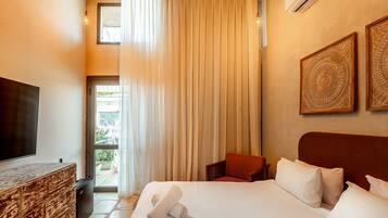 Habitación de hotel con cama, televisor, escritorio y ventana con cortinas.