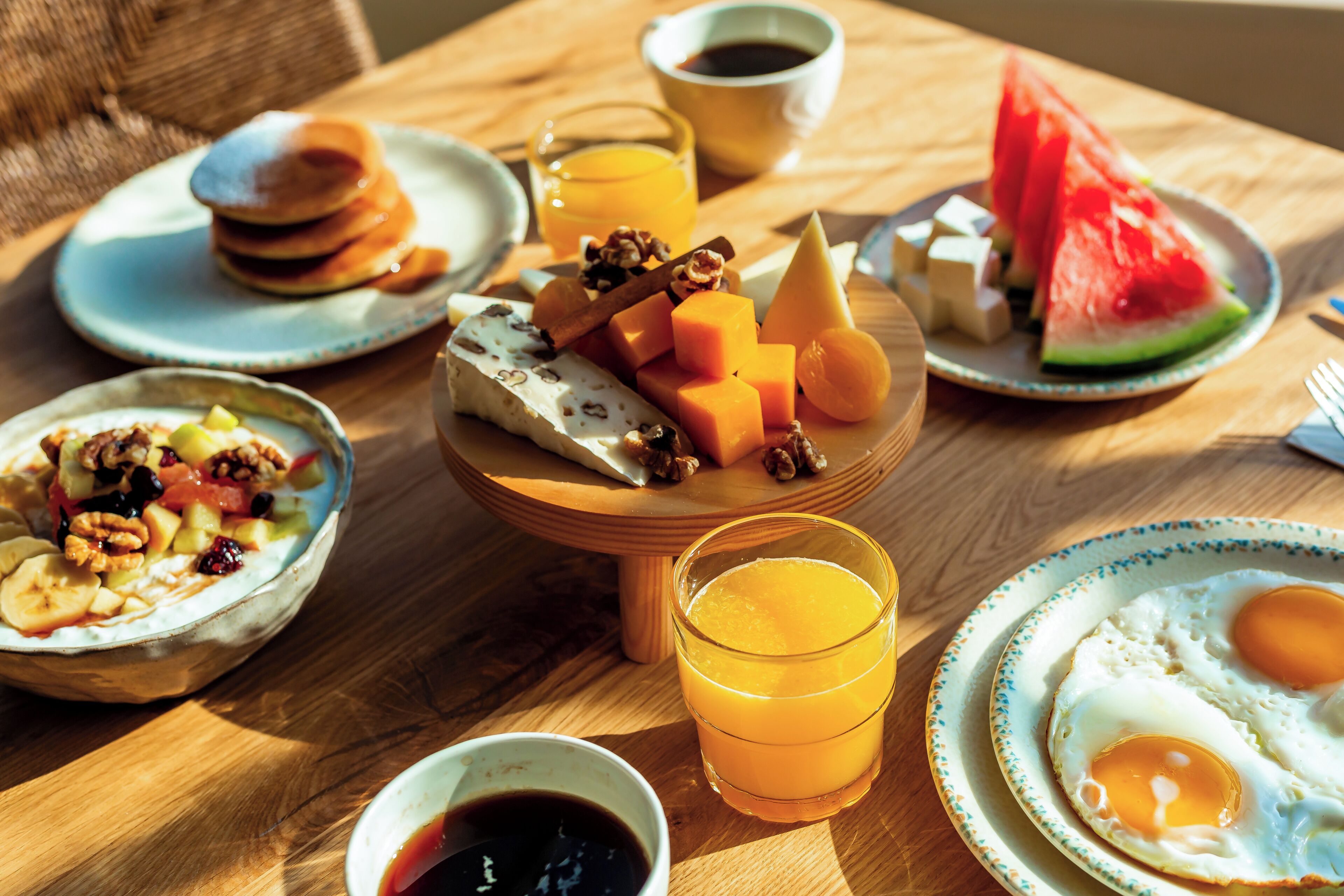 Une table de petit-déjeuner avec des crêpes, des fruits, du fromage et des œufs.