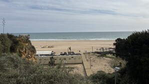 Una spiaggia con una battigia sabbiosa, alcune persone e un edificio con tetto piatto.