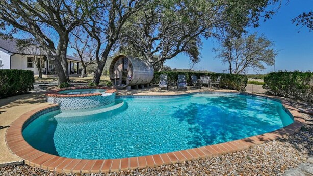 Una piscina con diseño curvo, bordeada por guijarros y un borde de azulejos.