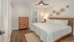 Une chambre à coucher avec un lit en bois, un ventilateur de plafond, une table de chevet avec une lampe et une commode.