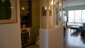 Eine moderne Küche mit grünen Schränken, einer weißen Arbeitsplatte und einem Fenster mit Blick auf einen Balkon.