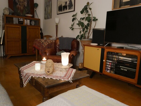 A cozy living room with a wooden coffee table, a television on a wooden cabinet, a potted plant, and a fireplace. - 5 pers. 3 rooms 70 m2 in luxury building, 1 mn from RER and Vincennes woods (Fontenay-sous-Bois)