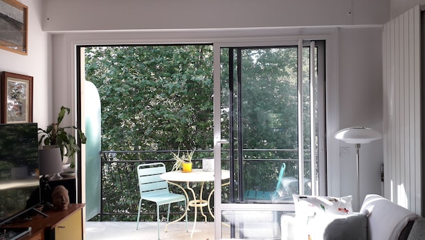 Ein Balkon mit Tisch, Stühlen, einem Blumentopf und einer Couch.