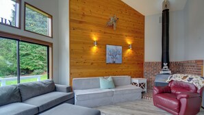 A modern living room with a grey sofa, a red leather chair, and a fireplace. - The Swedish Fish: Getaway on Lake Saint Clair! (Olympia)