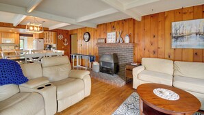 A cozy living room with a fireplace, leather sofas, and wooden walls. - The Swedish Fish: Getaway on Lake Saint Clair! (Olympia)