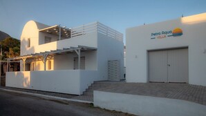 Una villa blanca moderna con un área de estar cubierta al aire libre, un garaje y un cartel que dice 'Petra Aqua Villa'.
