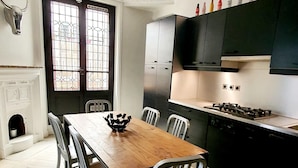 A modern kitchen with a dining area, featuring a wooden table and chairs, a stove, and black cabinets. - Jehan, 2BR/1BA, 4 people (París)