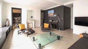 A modern living room with a glass coffee table, leather armchairs, a fireplace, and a flat-screen TV mounted on the wall. - Jehan, 2BR/1BA, 4 people (París)
