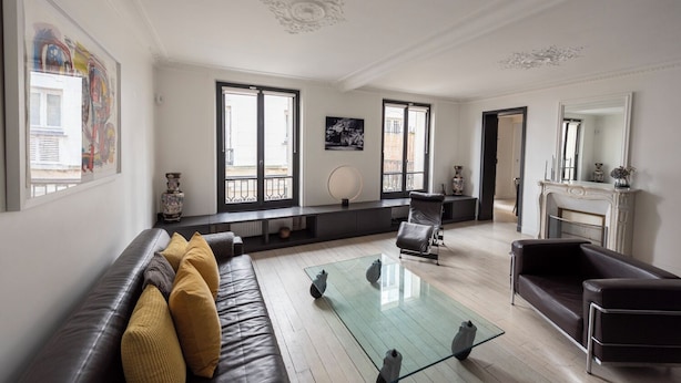 A spacious living room with a glass coffee table, leather sofas, and a fireplace. - Jehan, 2BR/1BA, 4 people (París)
