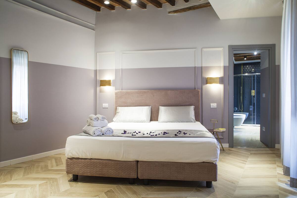 A bedroom with a large bed, two bedside tables, and a view of a bathroom.