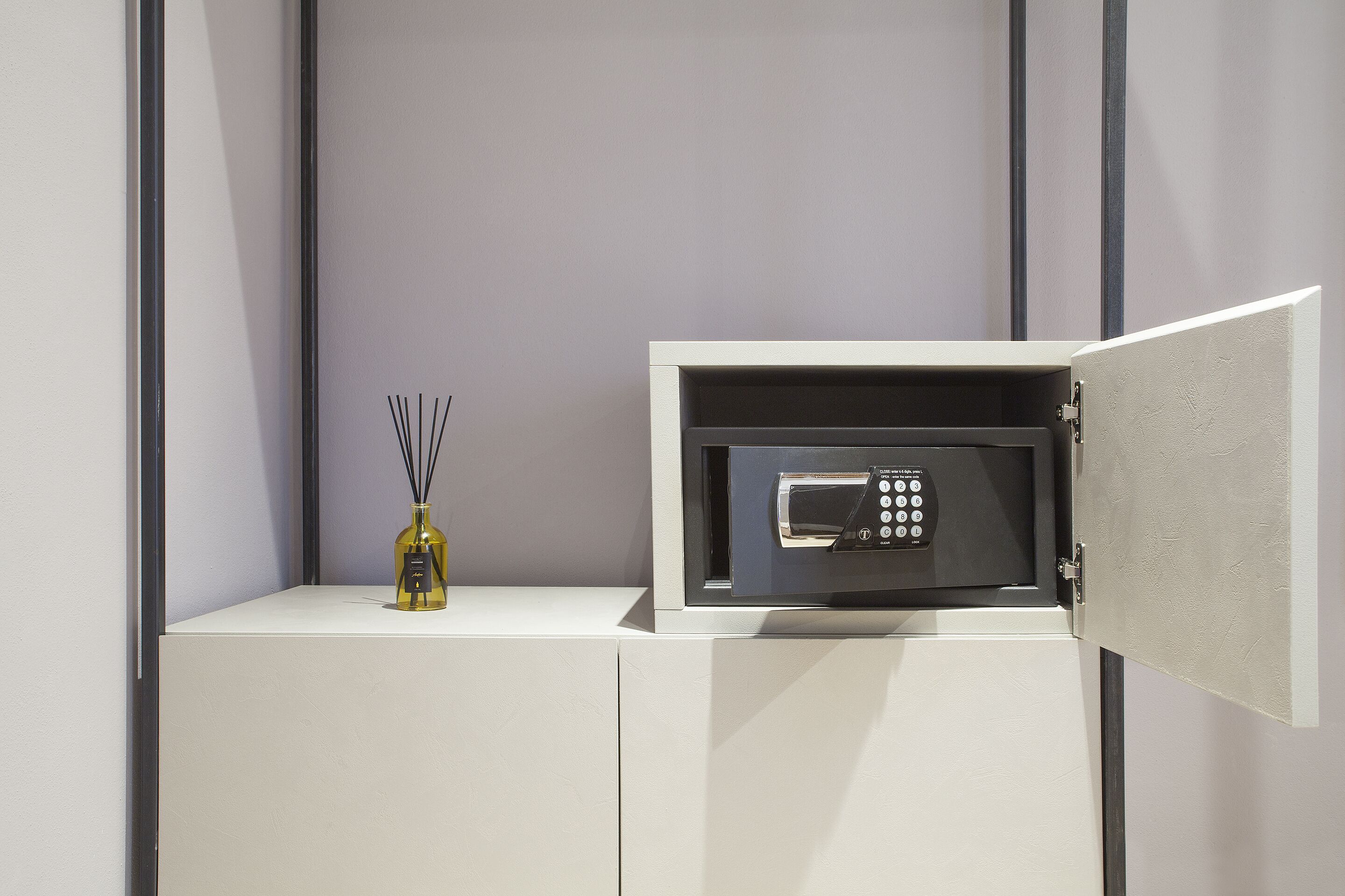 Un mini bar con un microondas, una botella de agua y una botella de perfume.