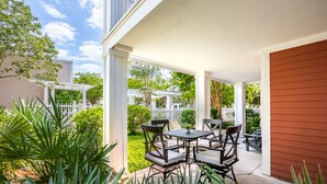 Un patio couvert avec des meubles d’extérieur, une clôture blanche et une végétation luxuriante.