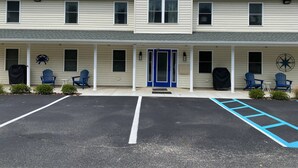 A two-story building with a covered porch, outdoor seating, and a parking lot.
