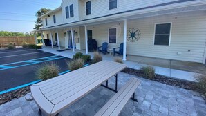 A two-story building with a covered porch, outdoor seating, and a picnic table.
