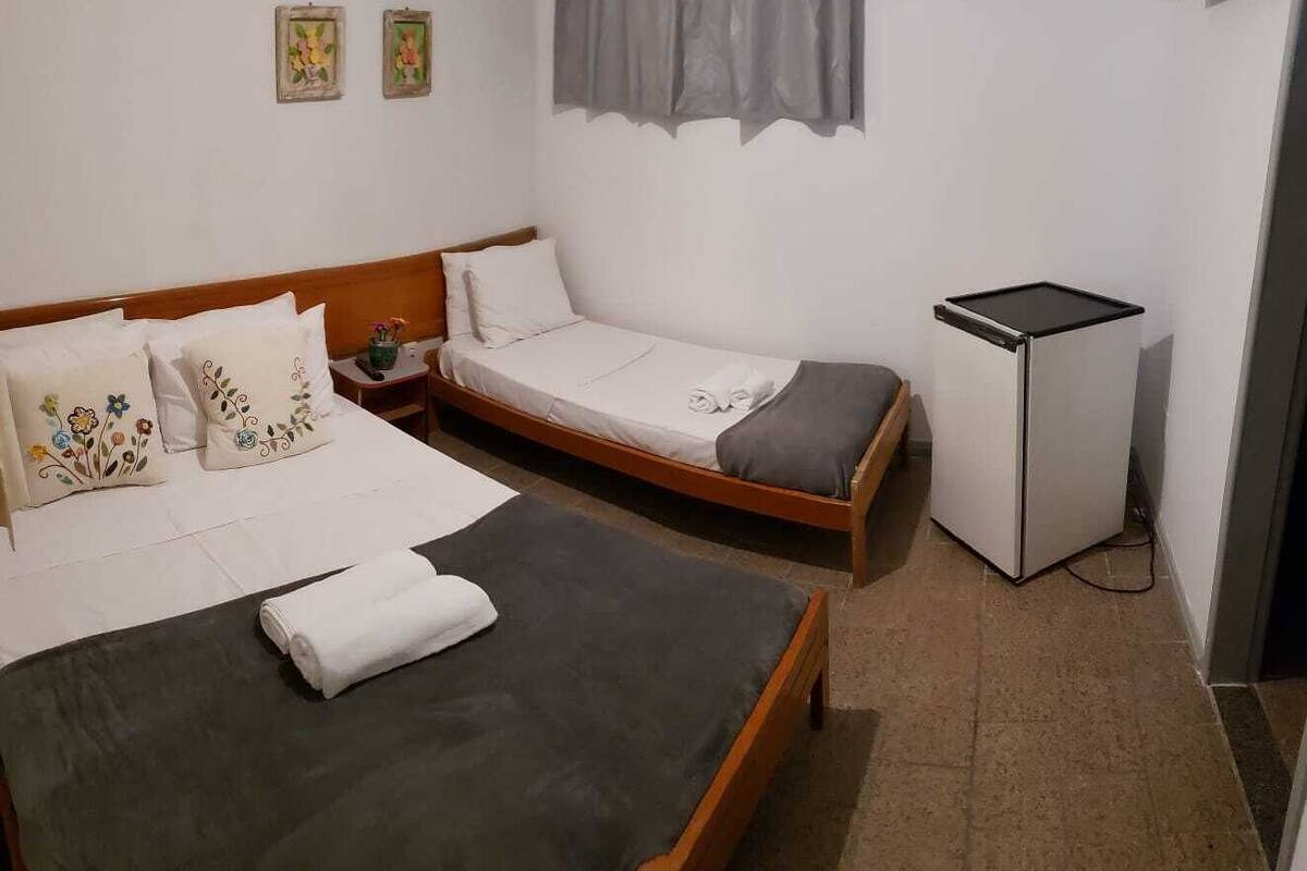 Una habitación con dos camas individuales, un escritorio pequeño y un refrigerador.