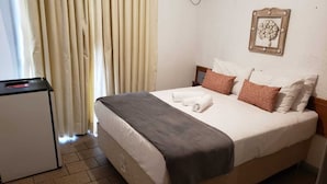 Una camera d'albergo con un letto, una scrivania e una finestra con tende.