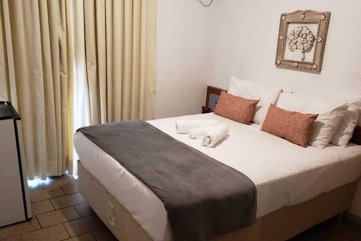 Una habitación de hotel con cama, escritorio y ventana con cortinas.