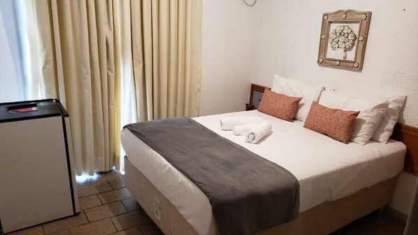 A hotel room with a bed, a desk, and a window with curtains.